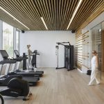 Sovereign Estates   Modern gym with treadmills and bikes along a glass wall featuring a wooden slat ceiling and weight machine 2026 Modern gym with treadmills and bikes along a glass wall featuring a wooden slat ceiling and weight machine