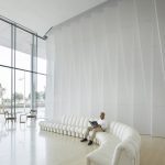 Sovereign Estates   Man sitting on a long white curved sofa reading a magazine in a bright minimalist lobby with floor to ceiling glass walls at the left edge of the room 2026 Man sitting on a long white curved sofa reading a magazine in a bright minimalist lobby with floor to ceiling glass walls at the left edge of the room