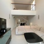 Sovereign Estates   Open two story living area with a beige sectional sofa black oval coffee table and a TV on a glass TV stand bright airy space with a mezzanine balcony above 2026 Open two story living area with a beige sectional sofa black oval coffee table and a TV on a glass TV stand bright airy space with a mezzanine balcony above