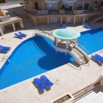 Sovereign Estates   Hotel pool area with a bright blue irregularly shaped pool central circular water feature and numerous blue lounge chairs along the beige surrounding buildings 2026 Hotel pool area with a bright blue irregularly shaped pool central circular water feature and numerous blue lounge chairs along the beige surrounding buildings