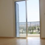 Sovereign Estates   Empty beige walled room with light wood floor and an open glass door leading to a balcony landscape and sea visible beyond railing 2026 Empty beige walled room with light wood floor and an open glass door leading to a balcony landscape and sea visible beyond railing