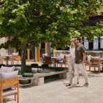 Sovereign Estates   Couple walking through an outdoor restaurant terrace with wooden tables chairs and a large tree providing shade 2026 Couple walking through an outdoor restaurant terrace with wooden tables chairs and a large tree providing shade