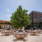 Sovereign Estates   Outdoor restaurant courtyard with a large tree at center wooden seating and a modern glass front building on the right 2026 Outdoor restaurant courtyard with a large tree at center wooden seating and a modern glass front building on the right
