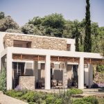 Sovereign Estates   Modern white house with stone accents and a wooden pergola outdoor seating and lush garden surrounding the façade 2026 Modern white house with stone accents and a wooden pergola outdoor seating and lush garden surrounding the façade