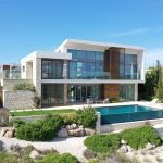 Sovereign Estates   Contemporary two story villa with glass walls stone and wood accents and a rectangular swimming pool in a landscaped yard 2026 Contemporary two story villa with glass walls stone and wood accents and a rectangular swimming pool in a landscaped yard