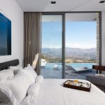 Sovereign Estates   Modern hotel room with a white bed breakfast tray and a balcony overlooking mountains and a pool 2026 Modern hotel room with a white bed breakfast tray and a balcony overlooking mountains and a pool