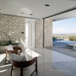 Sovereign Estates   Open plan living area with stone walls wooden staircase and marble floor opening to a terrace with an infinity pool and lounge chairs overlooking a valley 2026 Open plan living area with stone walls wooden staircase and marble floor opening to a terrace with an infinity pool and lounge chairs overlooking a valley