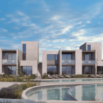 Sovereign Estates   Row of modern beige villas with large glass windows and a curved pool in the foreground under a blue sky and wispy clouds 2026 Row of modern beige villas with large glass windows and a curved pool in the foreground under a blue sky and wispy clouds