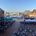 Sovereign Estates   Harbor scene with moored boats brick promenade buildings and outdoor seating under white tents 2026 Harbor scene with moored boats brick promenade buildings and outdoor seating under white tents