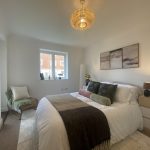 Sovereign Estates   Bright modern bedroom with a white bed layered linens and green throw pillows under a round wicker pendant light 2026 Bright modern bedroom with a white bed layered linens and green throw pillows under a round wicker pendant light