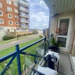 Sovereign Estates   Balcony scene with blue railing overlooking a lawn a path and a distant sea under a cloudy sky small table and chairs set on the balcony 2026 Balcony scene with blue railing overlooking a lawn a path and a distant sea under a cloudy sky small table and chairs set on the balcony