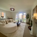 Sovereign Estates   Bright living room with a curved white sectional sofa beige rug and large windows opening to a balcony 2026 Bright living room with a curved white sectional sofa beige rug and large windows opening to a balcony