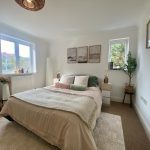 Sovereign Estates   Bright bedroom with a neatly made bed beige bedding and pastel cushions flanked by white nightstands and wall art 2026 Bright bedroom with a neatly made bed beige bedding and pastel cushions flanked by white nightstands and wall art