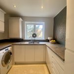 Sovereign Estates   Bright U shaped kitchen with white cabinets stainless steel sink under a window and a washing machine under the counter to the left 2026 Bright U shaped kitchen with white cabinets stainless steel sink under a window and a washing machine under the counter to the left