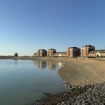 Sovereign Estates   Calm seaside with a sandy beach and a row of red brick apartment buildings along the shore under a clear blue sky 2026 Calm seaside with a sandy beach and a row of red brick apartment buildings along the shore under a clear blue sky