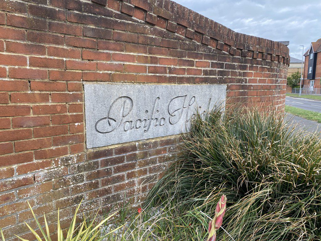 IMG_25_20_largejpg - Sovereign Estates Sovereign Estates Stone plaque with cursive inscription mounted on a red brick wall with ornamental grasses in the foreground and a street in the background 2026 Stone plaque with cursive inscription mounted on a red brick wall with ornamental grasses in the foreground and a street in the background