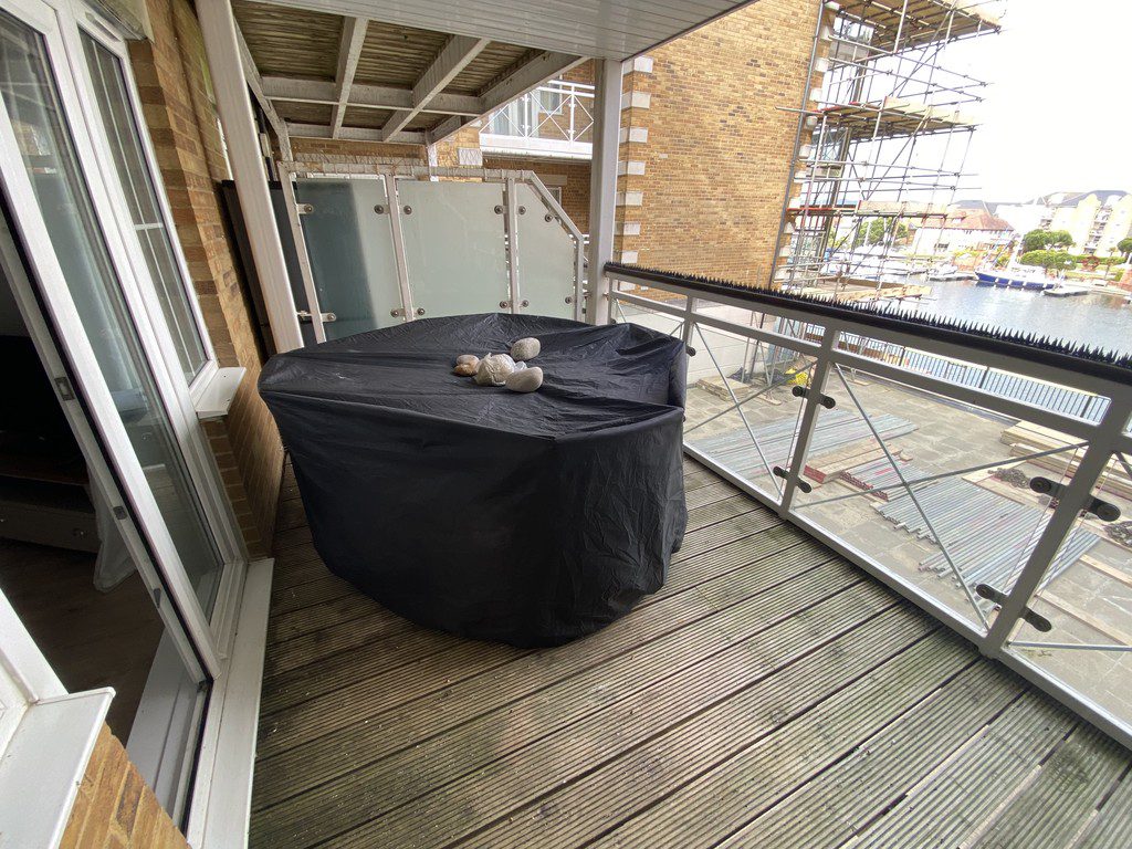 IMG_25_22_largejpg - Sovereign Estates Sovereign Estates Balcony with a round table covered by a black cloth and a few rocks on top overlooking a construction site and water beyond the railing 2026 Balcony with a round table covered by a black cloth and a few rocks on top overlooking a construction site and water beyond the railing