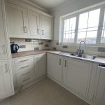 IMG_25_27_largejpg - Sovereign Estates Sovereign Estates L shaped kitchen with light gray cabinets wood countertop and a double sink under a large window 2026 L shaped kitchen with light gray cabinets wood countertop and a double sink under a large window