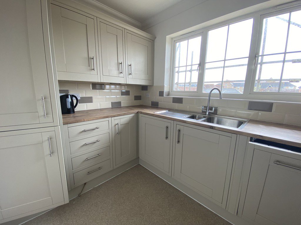 IMG_25_27_largejpg - Sovereign Estates Sovereign Estates L shaped kitchen with light gray cabinets wood countertop and a double sink under a large window 2026 L shaped kitchen with light gray cabinets wood countertop and a double sink under a large window