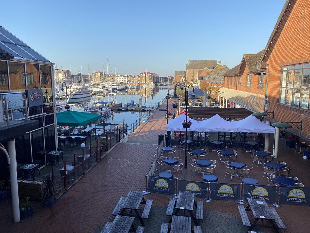 IMG_25_2_largejpg - Sovereign Estates Sovereign Estates Outdoor harbor side seating with blue chairs and white canopies along a brick promenade boats moored in the water and brick buildings nearby 2026 Outdoor harbor side seating with blue chairs and white canopies along a brick promenade boats moored in the water and brick buildings nearby
